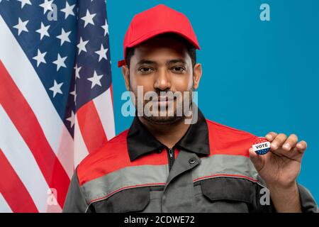 Junge seriöse Werkstatt der hispanischen Ethnie zeigt Ihnen Stimme Insignien Stockfoto