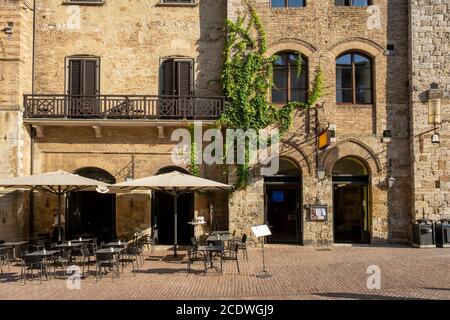 Café-Tische und Stühle vor einem Steingebäude in der Toskana, Italien Stockfoto