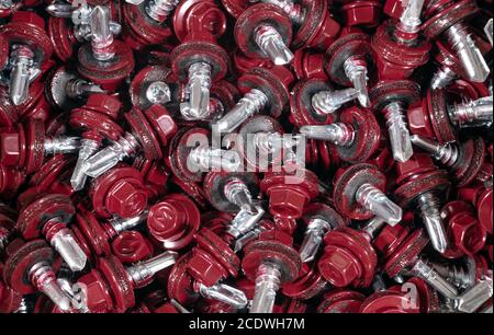 Draufsicht auf Dachschrauben Hintergrund Textur. Rote Dachschrauben Hintergrund. А Bündel von selbstschneidenden Schrauben für die Befestigung des Daches mit roten Köpfen Stockfoto