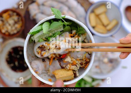 Draufsicht die Leute frühstücken mit hausgemachten veganen vietnamesischen Reisnudeln, Nahaufnahme Hand halten Schüssel mit gefüllten Pfannkuchengericht auf Lebensmittel Hintergrund Stockfoto