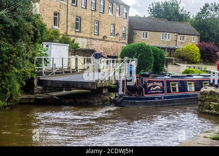 Ein schmales Boot fährt durch eine Schaukelbrücke auf dem Leeds - Liverpool Canal in Skipton, Yorkshire. Stockfoto