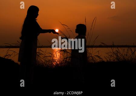 Orange Silhouette Sonnenuntergang der Mutter, die Sonne der Tochter bei Bacreswar Mutter birbhum West Bengalen Indien am 5. Januar 2020 Stockfoto