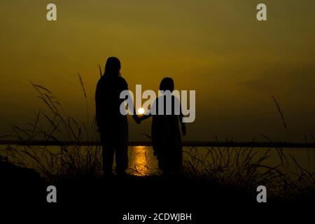 Grüne Silhouette Sonnenuntergang von Mutter und Tochter halten Hände an Bacreswar Mutter birbhum Stockfoto