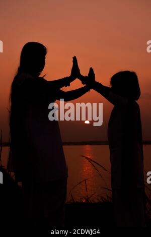 Am 5. Januar 2020 orange Silhouette Sonnenuntergang von Mutter und Tochter bei bacreswar Damm, birbhum, West Bengalen, Indien Stockfoto