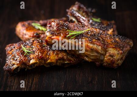 Gegrillte Schweinebrippen mit Rosmarin auf Holzhintergrund. Konzept für Grillgerichte. Stockfoto