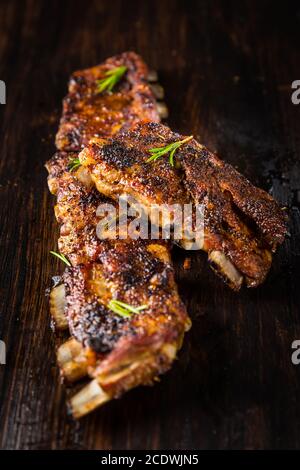 Gegrillte Schweinebrippen mit Rosmarin auf Holzhintergrund. Konzept für Grillgerichte. Stockfoto