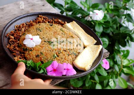 Vietnamesische hausgemachte Speisen für die Mittagszeit, Frau Hand halten gebratenen Reisplatte mit Tofu bereit zu essen, einfache vegane Lebensmittel für Vegetarier aus der Sicht Stockfoto