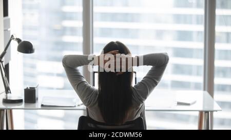 Rückansicht junge Geschäftsfrau lehnte sich zurück in einem bequemen Stuhl Stockfoto