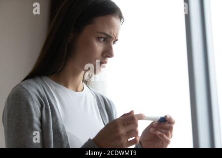 Close up ängstlich unglücklich junge Frau hält Kunststoff Schwangerschaft Test Stockfoto