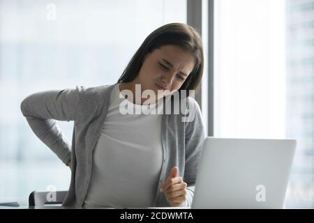 Gestresste müde junge Geschäftsfrau leiden unter Rückenschmerzen im Büro Stockfoto