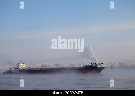 Lange Lastkahn, Fluss im kalten Winter. Stockfoto