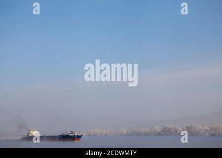 Lange Lastkahn, Fluss im kalten Winter. Stockfoto