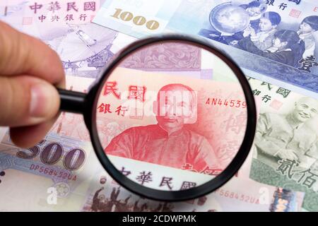 Neuer Taiwan-Dollar in einer Lupe ein geschäftlicher Hintergrund Stockfoto