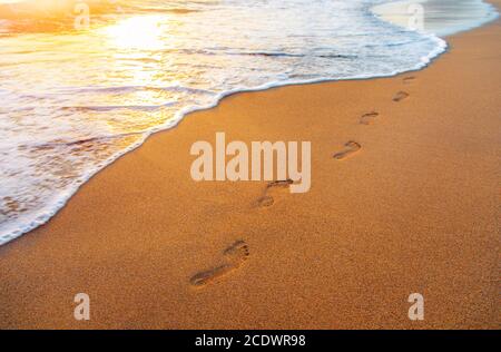Strand, Wellen und Spuren bei Sonnenuntergang Stockfoto