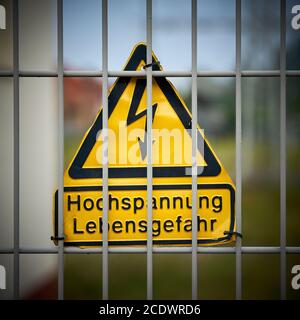 Schild mit der Aufschrift Hochspannung Lebensgefahr an Ein Zaun Stockfoto