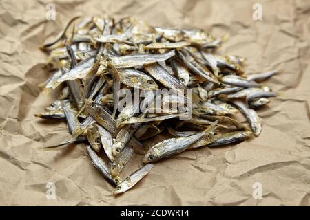 Getrocknete kleine gesalzene Sardelle oder Tüll Fisch Haufen auf zerknittertem Papier Hintergrund. Biersnack. Stockfoto