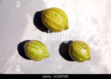 Bunte rosa Zitronen oder rosa-fleischige Eureka Zitronen auf grauem Betontisch, Draufsicht. Drei ganze Zitrusfrüchte mit gestreifter Rinde Stockfoto