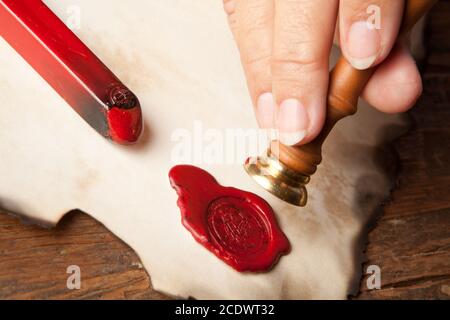 Hand mit altem Pergament oder Diplomrolle mit Wachssiegel Stockfoto