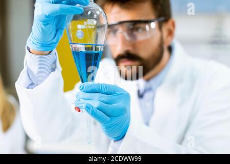 Forscher arbeiten mit blauer Flüssigkeit am Separationstrichter in der Labor Stockfoto