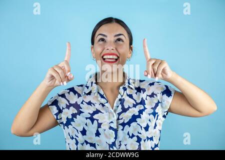 Junge schöne Frau trägt Sonnenbrille über isolierten blauen Hintergrund lächelnd, Blick und zeigt mit Fingern und erhobenen Armen. Stockfoto