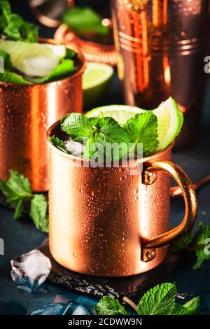 Moscow Mule Cocktail in Kupferkrug mit Limette, Ingwer Bier, Wodka und Minze. Blauer Tisch, Werkzeuge für Kupferbalken, Kopierbereich Stockfoto