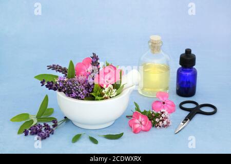 Kräutermedizin Zubereitung mit Blumen & Kräutern in einem Mörser mit Stößel & Aromatherapie ätherischen Ölflaschen. Stillleben für die naturheilkundliche Gesundheitsversorgung Stockfoto