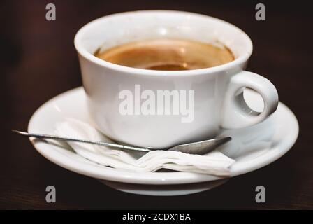 Nahaufnahme einer Tasse starken, schaumigen Espresso auf einer rauhen, braunen Holzoberfläche. Selektiver Fokus Makroaufnahme mit Stockfoto