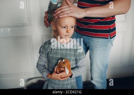 Vater Kämme und helfen Tochter Dressing Uniform Vorbereitung zurück in die Schule. Stockfoto