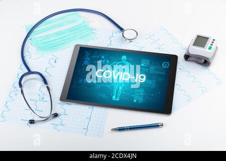Tablett-pc und Arztwerkzeuge mit COVID-19-Beschriftung, Coronavirus-Konzept Stockfoto