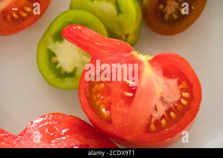 In Scheiben geschnittene Tomaten in verschiedenen Farben auf einem Teller Stockfoto