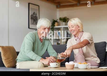 Seniorenpaar sitzt auf dem Sofa und trinkt gemeinsam Tee Das Wohnzimmer Stockfoto