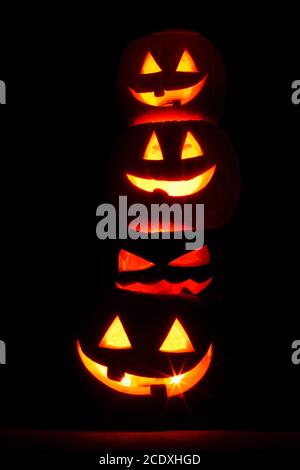 Haufen glühender geschnitzter Halloween Kürbisse auf schwarzem Hintergrund Stockfoto