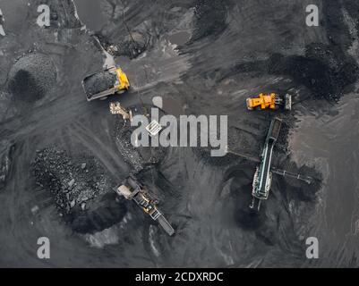 Tagebauminenindustrie, Bagger lädt Kohle in einen industriellen Brecher. Draufsicht Antenne Stockfoto