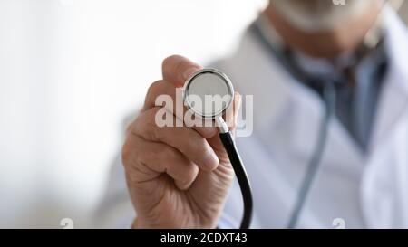 Nahaufnahme reifer Arzt hält Stethoskop, medizinische Untersuchung Stockfoto