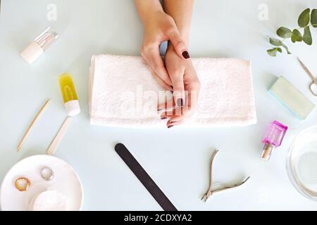 Frau sitzt am Tisch mit Maniküre Werkzeuge Stockfoto