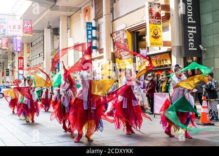 Japanisches Team von Kindern, 9-10 Jahre alt, yosakoi Tänzer tanzen in der Einkaufspassage und drehen um Kleidung am Ende der Stange. Bewegungsunschärfe. Stockfoto