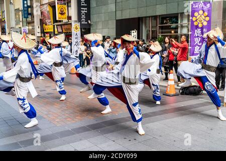 Japanisches Team von yosakoi-Tänzern in langärmeligen Yukata- und Strohbäuerhüten, die während des Kyusyu Gassai Festivals in Japan in einer Einkaufspassage tanzen Stockfoto