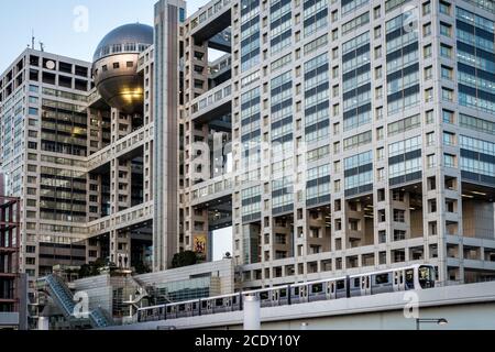 Odaiba, Tokyo, Japan - Fuji Television Headquarters Building und Yurikamome City Train, die vor dem einzigartig gestalteten Gebäude fahren. Stockfoto