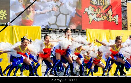 Japanisches Team von Kindern yosakoi Mädchen Tänzerinnen, 10-11 Jahre alt, auf der Bühne im Freien tanzen im Kyusyu Gassai Tanzfestival in Kumamoto, Japan. Stockfoto