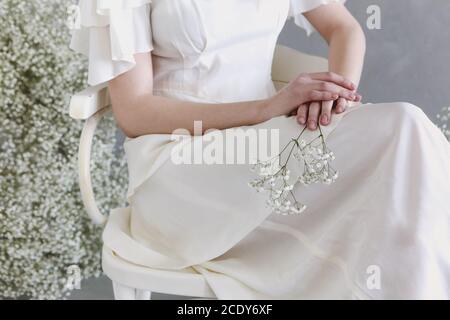 Crop weiblich in weißem Kleid hält Gypsophila Blume Stockfoto