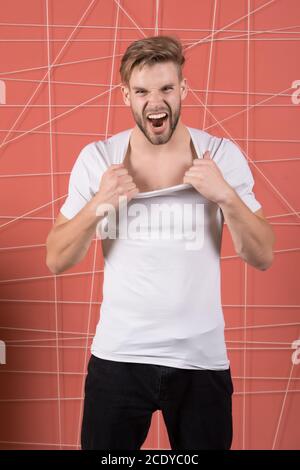 Mode Mann ziehen t-shirt Kragen mit Zorn. Fashion Model im lässigen Stil schreien auf rosa Hintergrund. Stockfoto