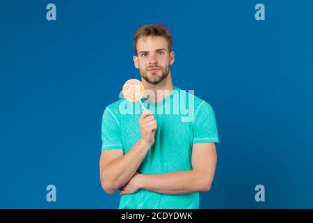 Lollipop Spaß. Mann essen großen bunten süßen Lutscher. Mann mit Borsten mag Lollipop. Cheat meal Konzept. Zucker schädlich für die Gesundheit. Kerl halten Lollipop candy violett unterlegt. Geschmack der Kindheit. Stockfoto