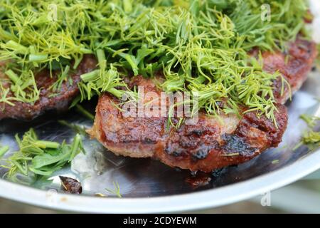 BBQ gebackenes Schweinefleisch bestreut mit Dill und Petersilie. Kochkonzept im Freien. Selektiver Fokus. Stockfoto
