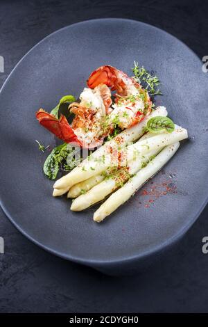 Traditionelle Grill stacheligen Hummerschwanz geschnitten und mit Weiß angeboten Spargel und Salat als Draufsicht in modernem Design Platte Stockfoto