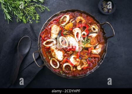 Traditioneller brasilianischer Fischeintopf Moqueca capixaba mit Fischfilet und Tintenfischringe in Tomatensauce als Draufsicht in A Rustikale Pfanne Stockfoto