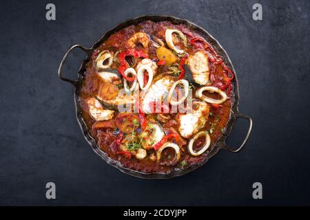 Traditioneller brasilianischer Fischeintopf Moqueca capixaba mit Fischfilet und Tintenfischringe in Tomatensauce als Draufsicht in A Rustikale Pfanne Stockfoto