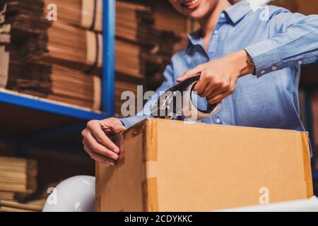 Nahaufnahme von Lagerarbeiter Frau Verpackung Karton mit Klebeband mit indischen Arbeiter Mann in lokalen Lager oder Fabrik, Industrie und Export Bus Stockfoto