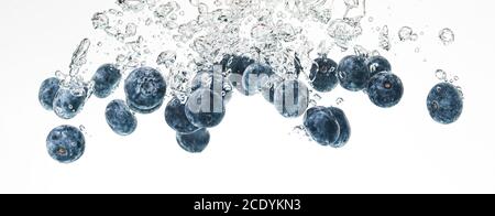Blaubeeren sinken in Wasser mit Luftblasen auf weißem Hintergrund. Stockfoto