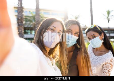 Nette blonde junge Frau nehmen ein Selfie mit ihren beiden Freundinnen tragen die Coronavirus Schutzmaske - Neu normal Leben mit Covid-19 Pandemie usi Stockfoto