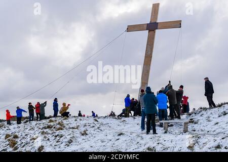 Menschen (Christen) verwenden Seile, um ein riesiges schweres hölzernes Osterkreuz (Faith Symbol) auf einem verschneiten Hügel zu heben - der Chevin, Otley, Yorkshire, Großbritannien. Stockfoto